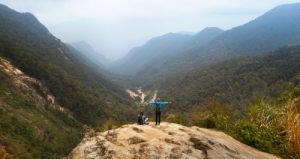 Voyageurs debout sur un rocher avec les mains levées, randonneur regardant la vallée en contrebas lors d'un voyage au Vietnam, femme appréciant le sommet d'un paysage de montagne en arrière plan