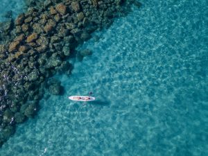 Vue aérienne d'un canoë dans l'eau flottant sur une mer transparente. Baigneurs en mer. Zambrone, Calabre, Italie. Plongée, détente et vacances d'été. Côtes, plages et rochers italiens