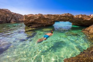 Blue Lagoon, Malta - Touriste faisant de la plongée avec tuba dans les grottes du Blue Lagoon sur l'île de Comino par une journée d'été ensoleillée avec un ciel bleu.