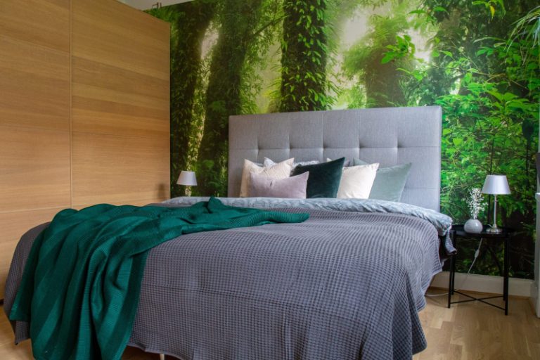 Lit avec literie grise, couverture verte contre un djungle photo wallpaper